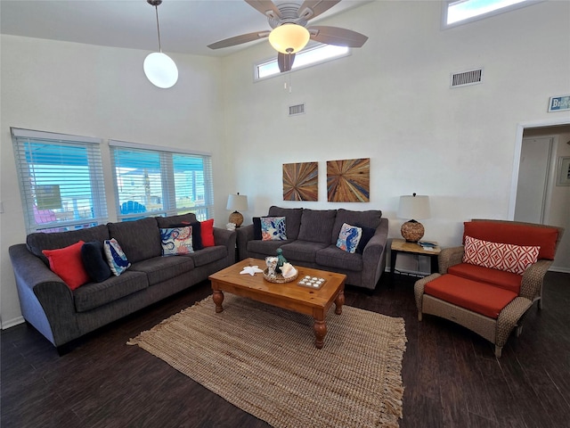 living room featuring a high ceiling, dark wood-type flooring, and ceiling fan