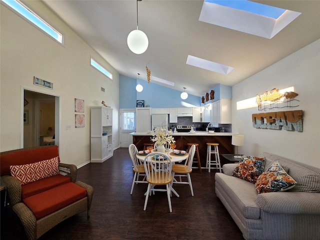 dining area with dark hardwood / wood-style flooring, a skylight, and high vaulted ceiling