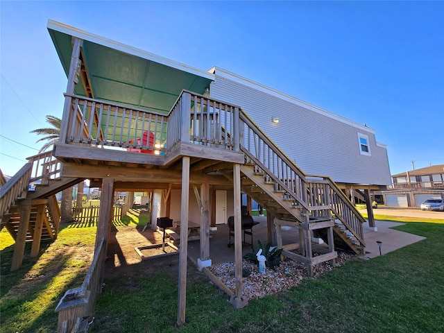 back of house featuring a wooden deck, a patio, and a lawn