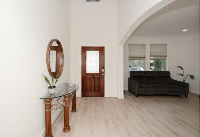 entrance foyer with ornamental molding and light hardwood / wood-style flooring