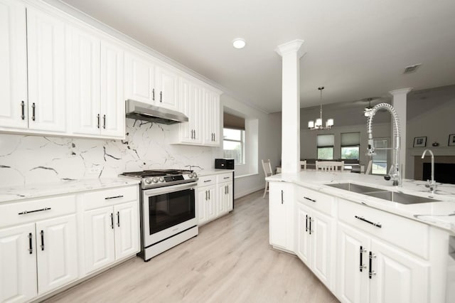 kitchen with stainless steel range with gas stovetop, decorative light fixtures, light stone countertops, a chandelier, and white cabinets