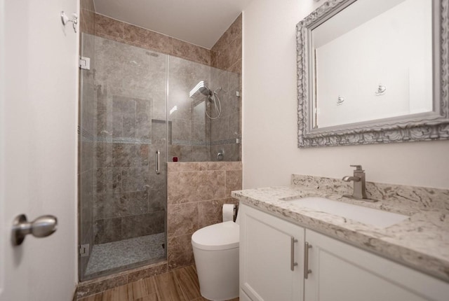 bathroom featuring toilet, hardwood / wood-style flooring, an enclosed shower, and vanity