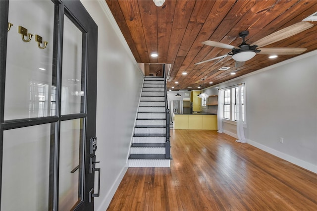 interior space with ceiling fan, wood-type flooring, crown molding, and wooden ceiling