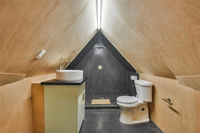 bathroom featuring toilet, vanity, lofted ceiling, and tile patterned flooring