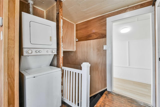 laundry room with stacked washing maching and dryer and wood walls