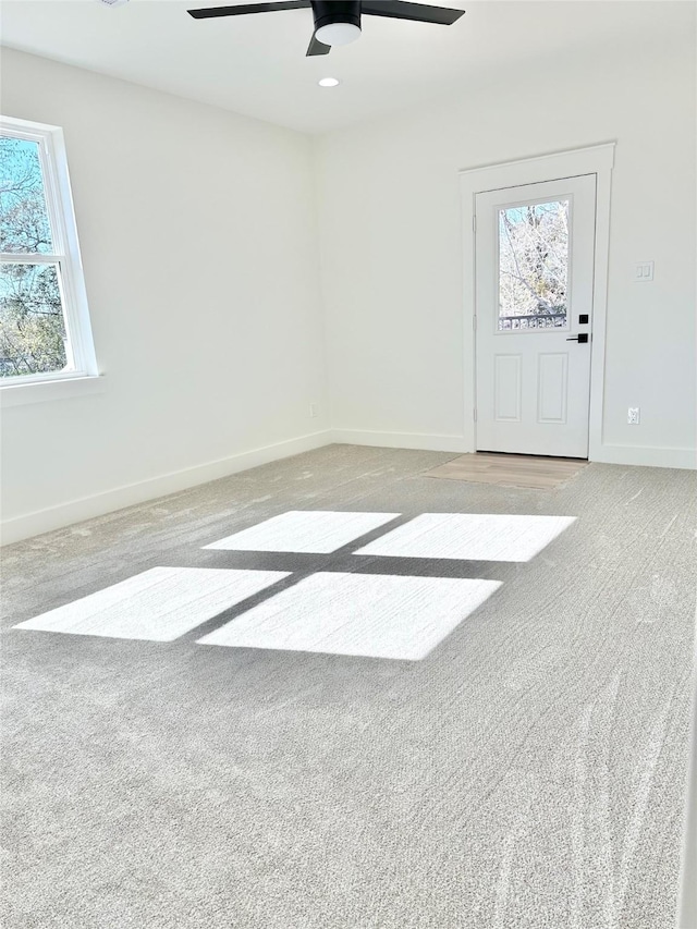 empty room featuring light carpet, ceiling fan, and a wealth of natural light