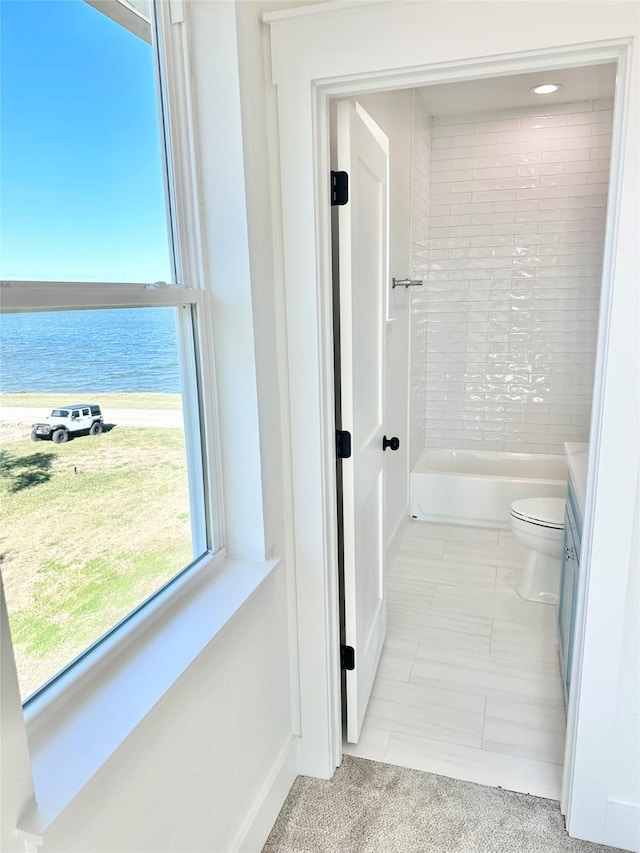 full bathroom with toilet, tiled shower / bath, vanity, tile patterned floors, and a water view