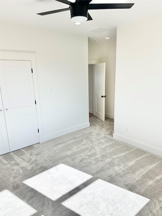 empty room featuring ceiling fan and light colored carpet