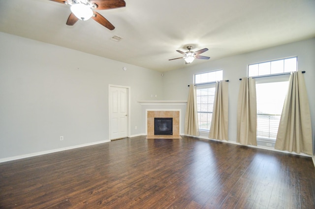 unfurnished living room featuring dark wood-type flooring, ceiling fan, and a tiled fireplace