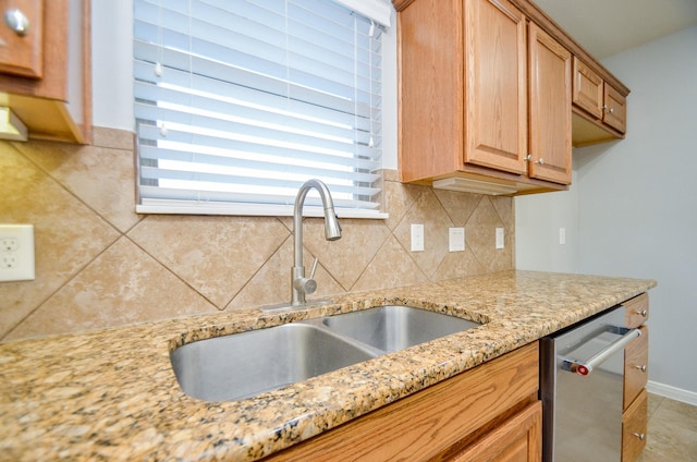 kitchen featuring tasteful backsplash, dishwasher, sink, and light stone countertops