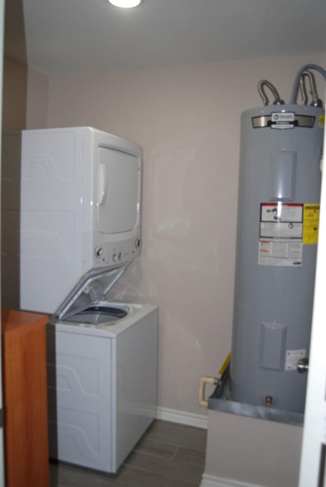 laundry room featuring stacked washing maching and dryer, water heater, and dark hardwood / wood-style floors