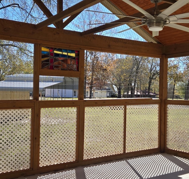 unfurnished sunroom with ceiling fan and vaulted ceiling