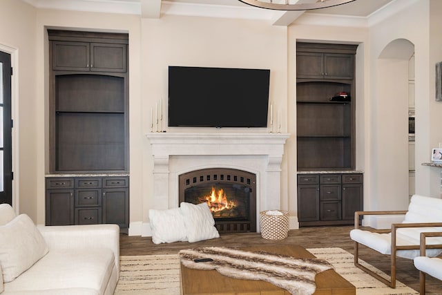 living room with dark wood-type flooring, built in features, and crown molding