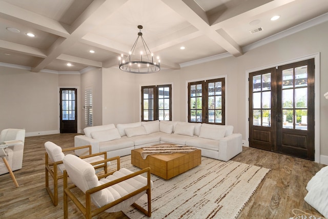 living room featuring light hardwood / wood-style floors, beam ceiling, an inviting chandelier, coffered ceiling, and french doors