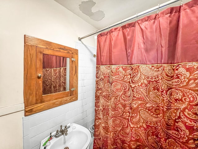 bathroom featuring sink, tile walls, and backsplash