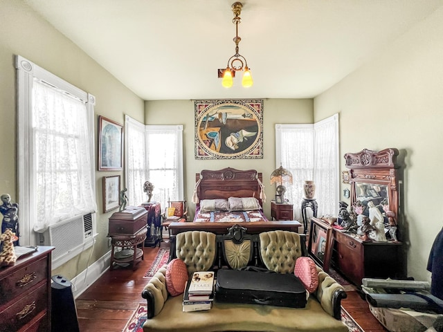 bedroom with dark hardwood / wood-style floors, cooling unit, and an inviting chandelier