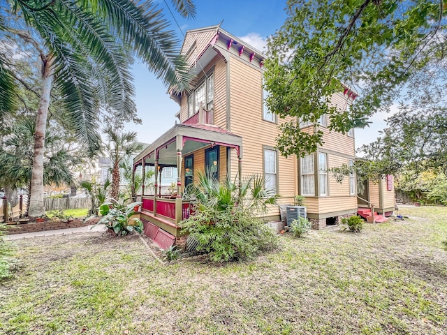 rear view of house featuring covered porch, a lawn, and central air condition unit