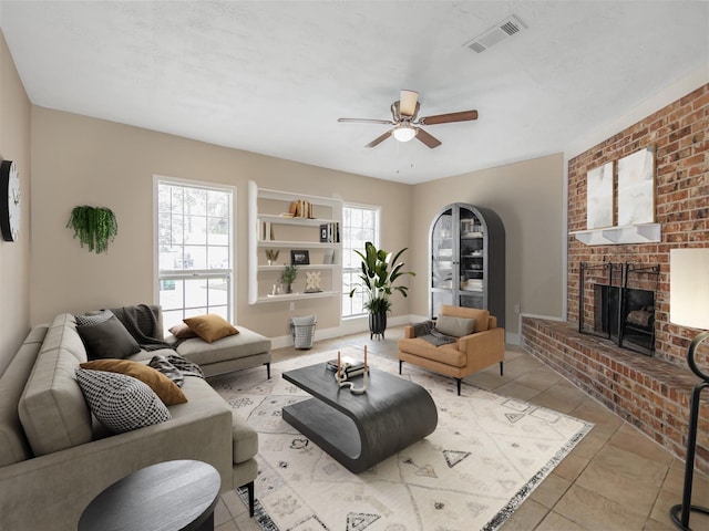 tiled living room with ceiling fan and a brick fireplace