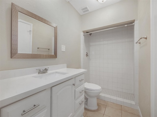 bathroom with toilet, vanity, tile patterned floors, and a tile shower