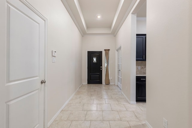 foyer entrance featuring a raised ceiling, light tile patterned floors, and crown molding