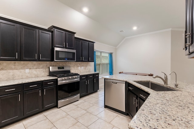 kitchen featuring stainless steel appliances, tasteful backsplash, lofted ceiling, light stone countertops, and sink