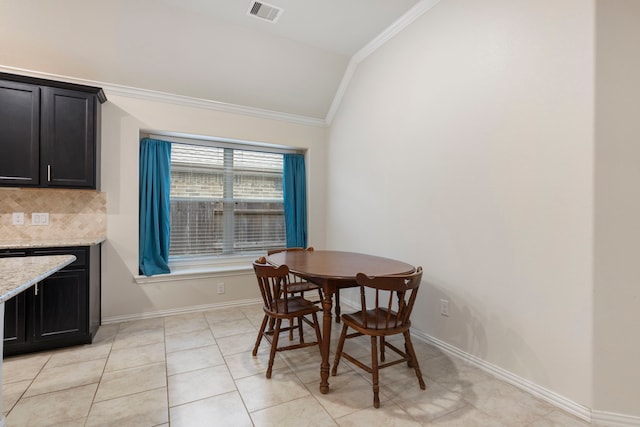 dining space featuring crown molding, light tile patterned floors, and lofted ceiling