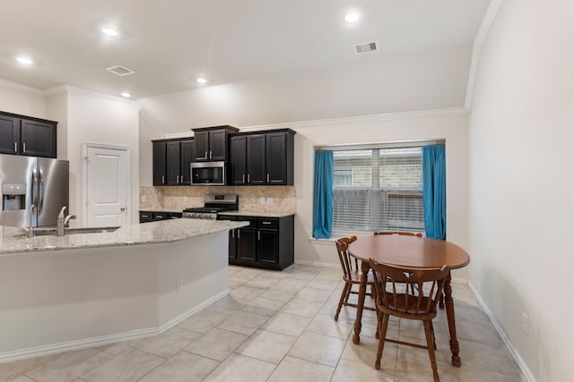 kitchen with lofted ceiling, backsplash, light tile patterned flooring, appliances with stainless steel finishes, and light stone counters