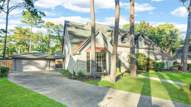 tudor house featuring a garage and a front lawn