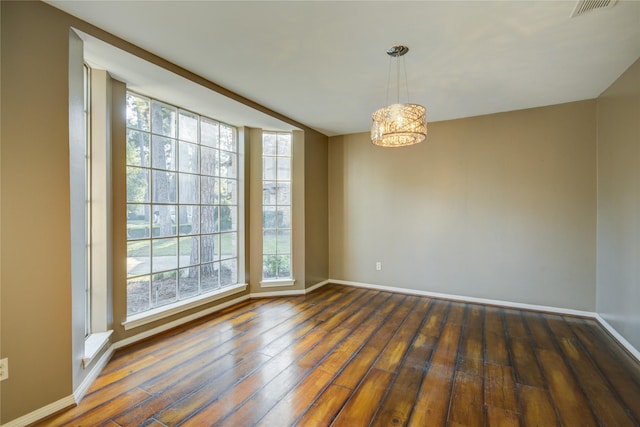 spare room featuring dark hardwood / wood-style floors and a notable chandelier