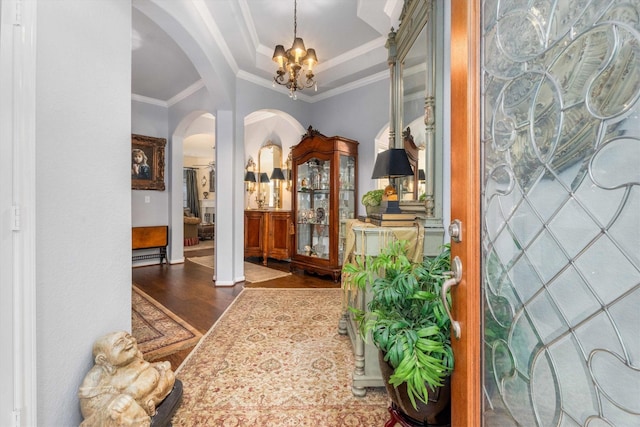 foyer featuring dark hardwood / wood-style floors, crown molding, a notable chandelier, and a tray ceiling