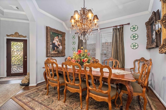 dining space with hardwood / wood-style floors, ornamental molding, and an inviting chandelier