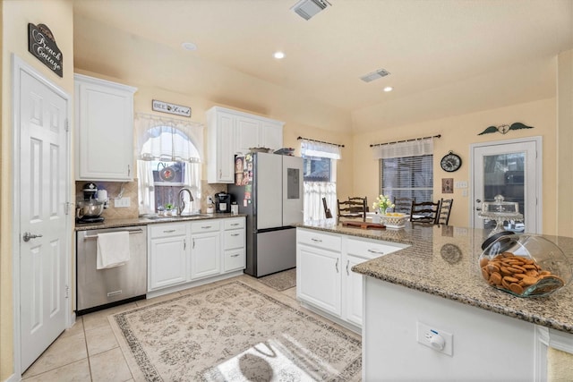 kitchen with white cabinetry, appliances with stainless steel finishes, stone counters, and light tile patterned flooring