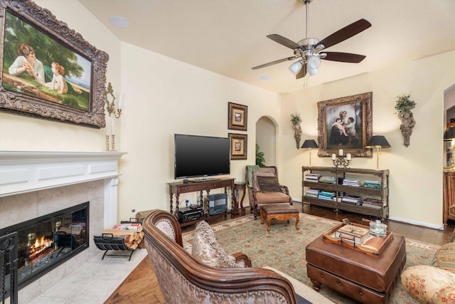 living room featuring ceiling fan, hardwood / wood-style floors, and a fireplace