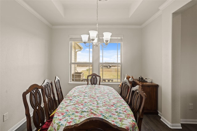 dining space with an inviting chandelier, dark hardwood / wood-style flooring, a tray ceiling, and ornamental molding