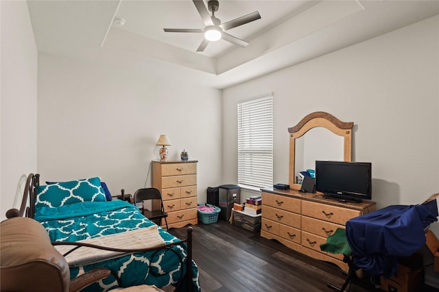 bedroom featuring ceiling fan, a tray ceiling, and dark hardwood / wood-style flooring