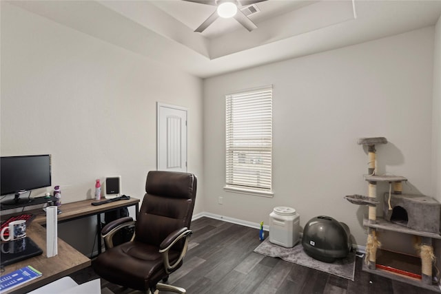 office space with ceiling fan, dark hardwood / wood-style flooring, and a tray ceiling