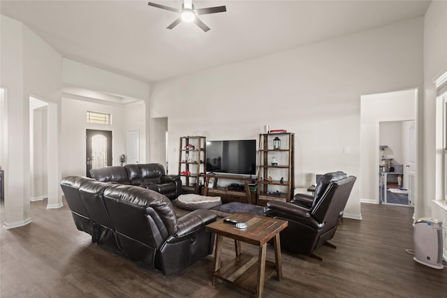 living room with ceiling fan, dark wood-type flooring, and a towering ceiling