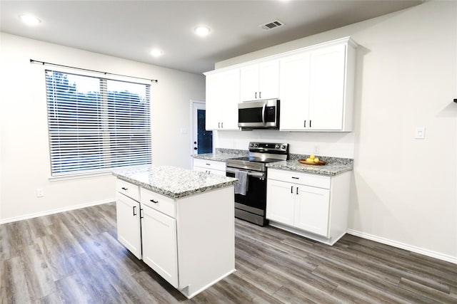 kitchen featuring white cabinets, light stone countertops, stainless steel appliances, and a kitchen island