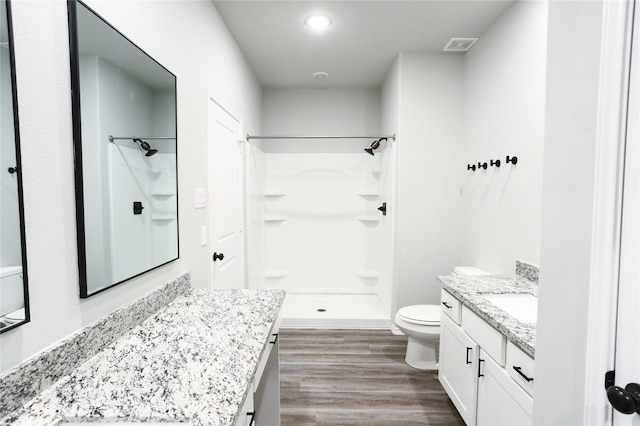 bathroom featuring toilet, a shower, hardwood / wood-style flooring, and vanity