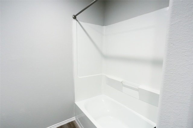 bathroom featuring hardwood / wood-style flooring and washtub / shower combination