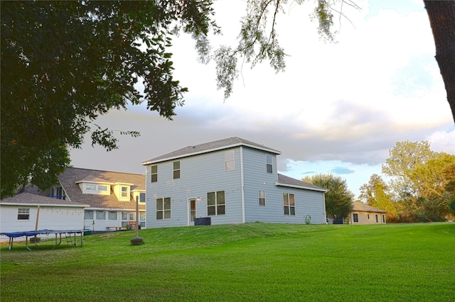 rear view of property with a lawn and a trampoline