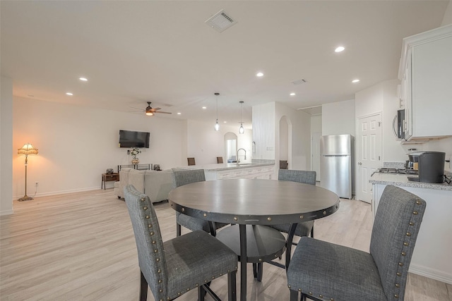 dining room featuring ceiling fan, light wood-type flooring, and sink