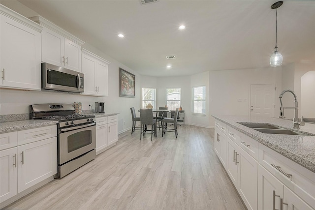 kitchen featuring light stone countertops, stainless steel appliances, white cabinets, and sink