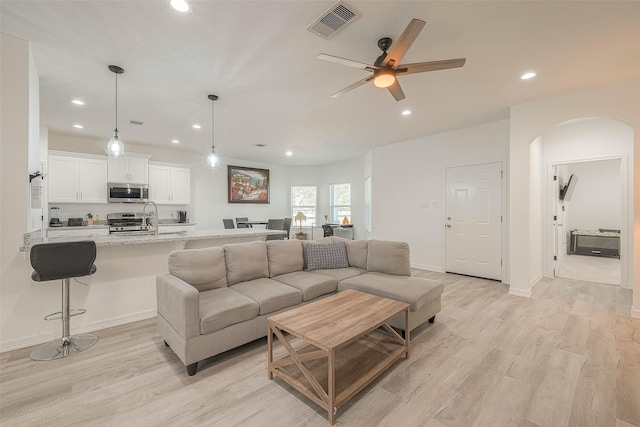 living room with ceiling fan, light wood-type flooring, and sink