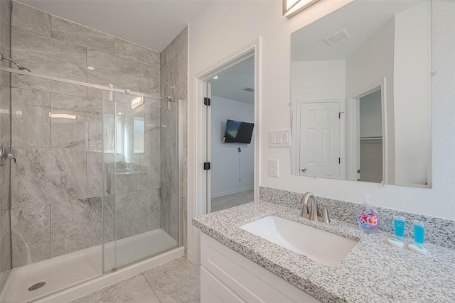 bathroom featuring a shower with shower door, vanity, and tile patterned flooring