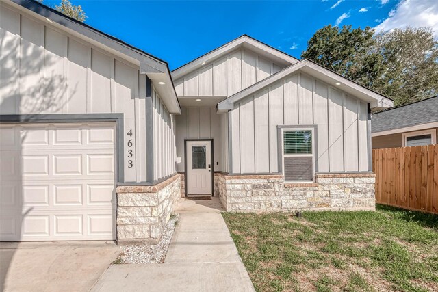 view of exterior entry with a garage and a lawn