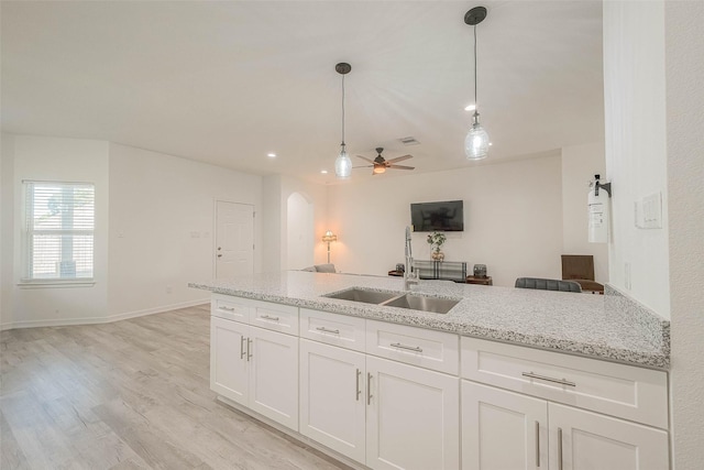 kitchen with ceiling fan, decorative light fixtures, sink, light stone countertops, and white cabinets