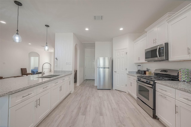 kitchen featuring light stone countertops, decorative light fixtures, white cabinetry, stainless steel appliances, and sink