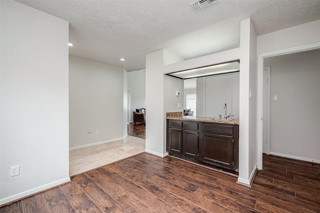 kitchen with dark brown cabinetry, visible vents, dark wood finished floors, and a sink