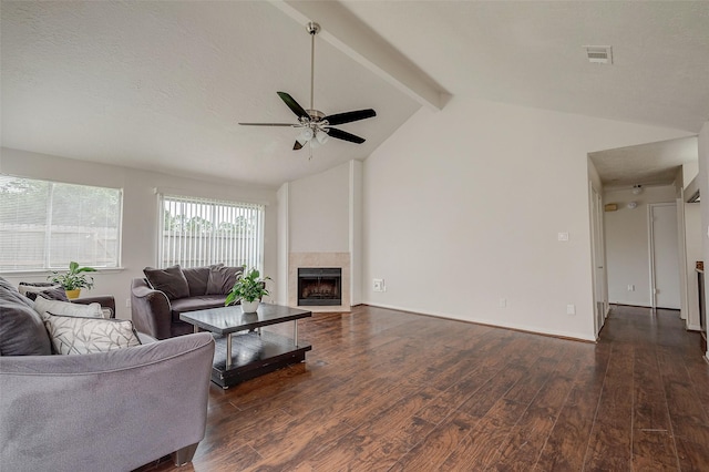 living room with visible vents, vaulted ceiling with beams, ceiling fan, a tiled fireplace, and dark wood-style floors